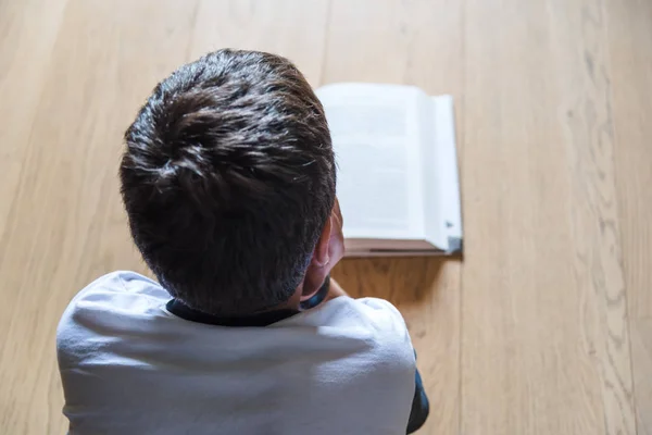 Ein kleiner Junge liest ein Buch. er liegt auf dem Boden. — Stockfoto