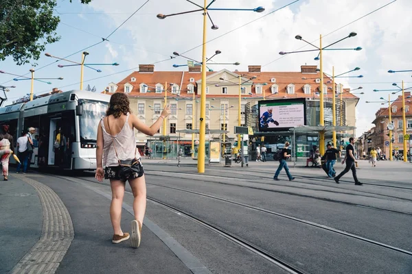 Graz meydanında tramvay için bekleyenler.