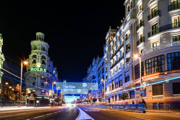 Madrid, Spain - December 8, 2017: Gran Via Street in Madrid at night on Christmas time. Long exposure shot with light trails of traffic and blurred people