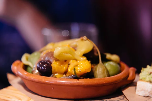 Gröna oliver och gul paprika i en keramikskål — Stockfoto