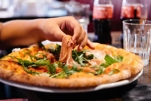 Hand av kvinna ta skinka bitar ur pizza tallrik i restaurang — Stockfoto