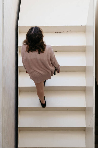Высокоугольный вид на молодую взрослую женщину, двигающуюся вверх по современной архитектуре
