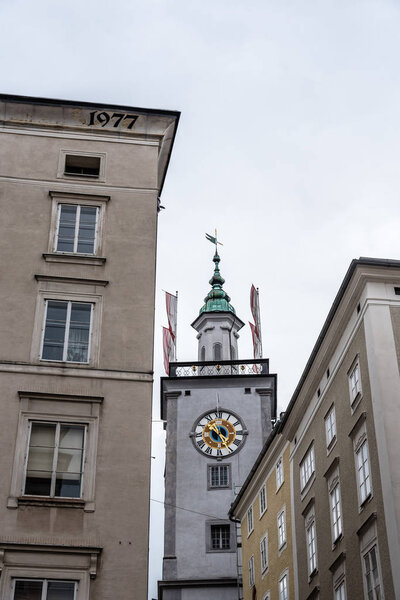 Low angle view of clock tower in historic city centre of Salzburg a cloudy day