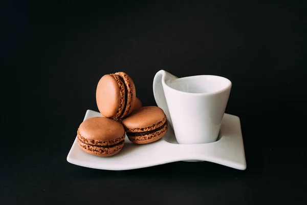 Tasse Kaffee und Makronen vor schwarzem Hintergrund — Stockfoto