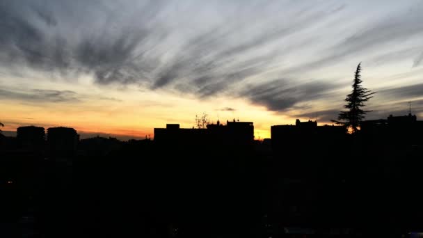 Timelapse del tramonto sulla silhouette del paesaggio urbano in inverno con camini e nuvole in movimento su sfondo arancione — Video Stock