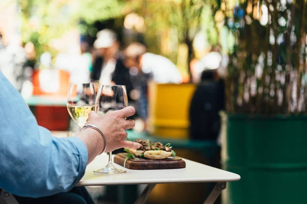 Vrouw geniet van een maaltijd met witte wijn in een trendy winkelgebied zittend op een terras — Stockfoto