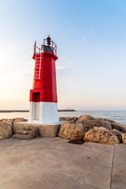 Yaz günbatımında limanın sonundaki kırmızı deniz feneri.