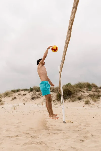 Giovane uomo che gioca a pallavolo sulla spiaggia estiva — Foto Stock