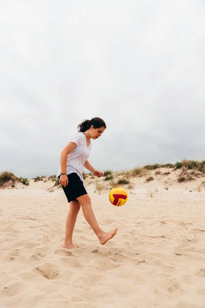Giovane donna con palla che gioca brutti scherzi con la palla sulla spiaggia estiva — Foto Stock