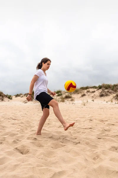 Giovane donna con palla che gioca brutti scherzi con la palla sulla spiaggia estiva — Foto Stock