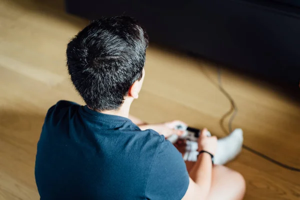 Tiener zitten op de vloer thuis spelen van een video game op de console — Stockfoto