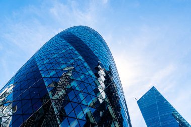 Londra 'daki ofis binalarının alçak açılı görüntüsü mavi gökyüzüne karşı. Gherkin.