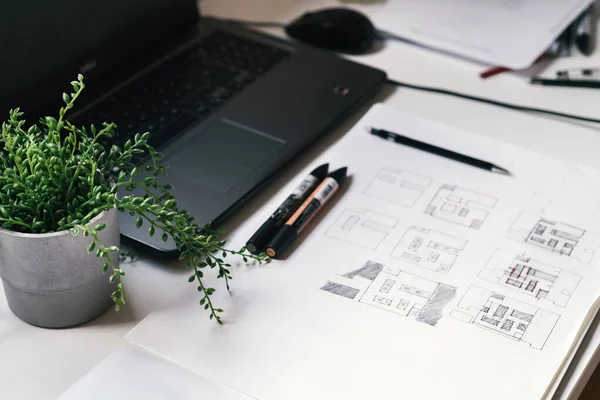 Architect Desk With Hand-drawn Plan Sketches, Color Markers, Laptop Computer, Green Plant And Pencil