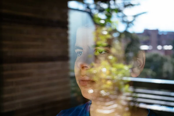 Niño mirando por la ventana a la calle esperando el final del confinamiento debido a la pandemia por COVID-19 — Foto de Stock