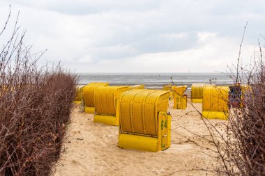 Kumsal ve Kuzey Denizi kıyısındaki Cuxhaven 'da tipik kapüşonlu plaj sandalyeleri.