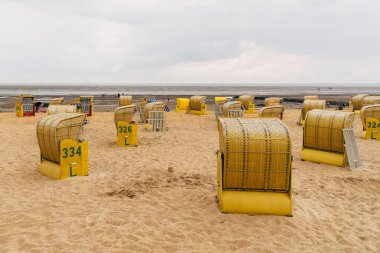 Kumsal ve Kuzey Denizi kıyısındaki Cuxhaven 'da tipik kapüşonlu plaj sandalyeleri.