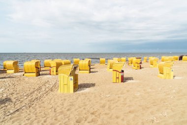 Kumsal ve Kuzey Denizi kıyısındaki Cuxhaven 'da tipik kapüşonlu plaj sandalyeleri.