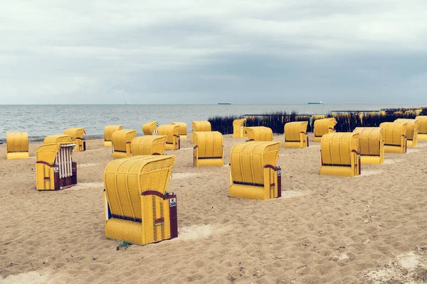Песчаный пляж и типичные пляжные стулья с капюшоном в Куксхавене на побережье Северного моря — стоковое фото