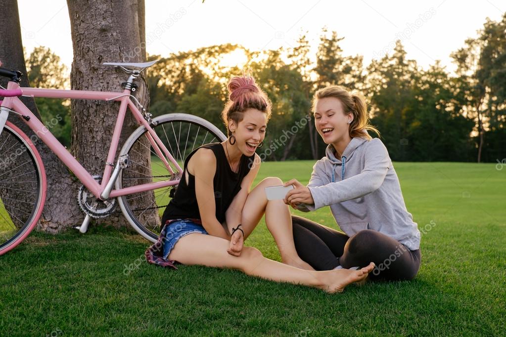 Best female friends with bicycle having fun