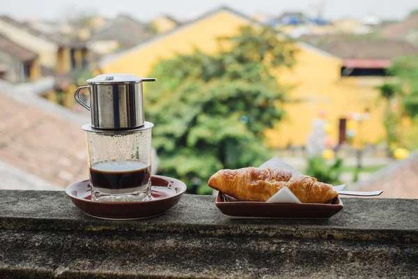 Вьетнамский кофе и круассан на столе — стоковое фото