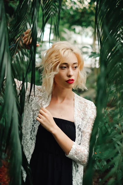 Beautiful blonde woman posing in tropical botanical garden — Stock Photo, Image