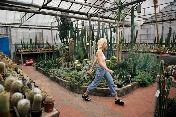 Beautiful blonde woman walking in cactus and succulent plants — Stock Photo, Image