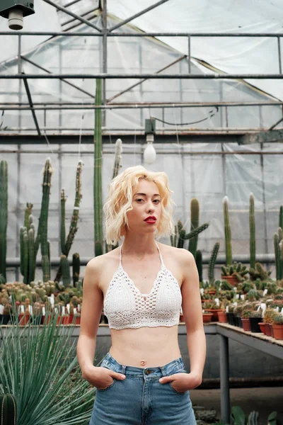 Porträt einer blonden jungen Frau zwischen Kaktus und saftigen Plan — Stockfoto