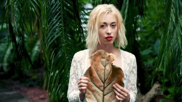Gentle portrait of blonde woman in tropical botanical garden — Stock Video
