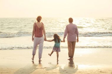 Karışık yarış aile çocukla denizde günbatımında oynuyor.