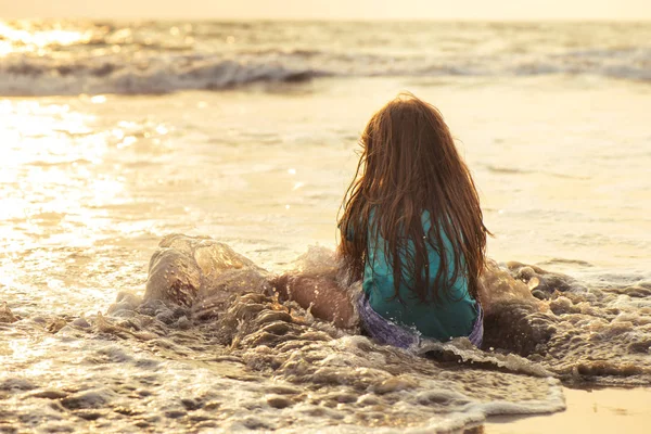 Pouco menina asiática jogando e se divertindo no mar ao pôr do sol — Fotografia de Stock