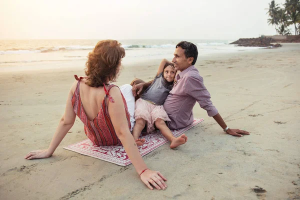 Familia de raza mixta feliz con niño cumplir puesta de sol en la playa — Foto de Stock