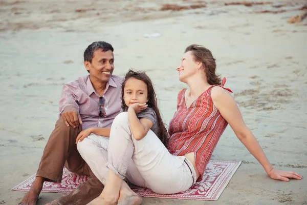 Familia de raza mixta feliz con niño cumplir puesta de sol en la playa — Foto de Stock