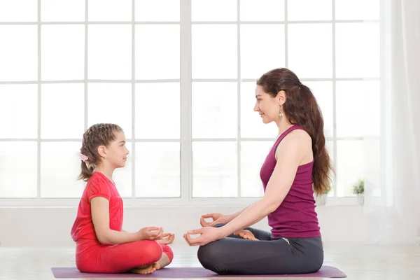 Ung mor och dotter gör yoga övning — Stockfoto