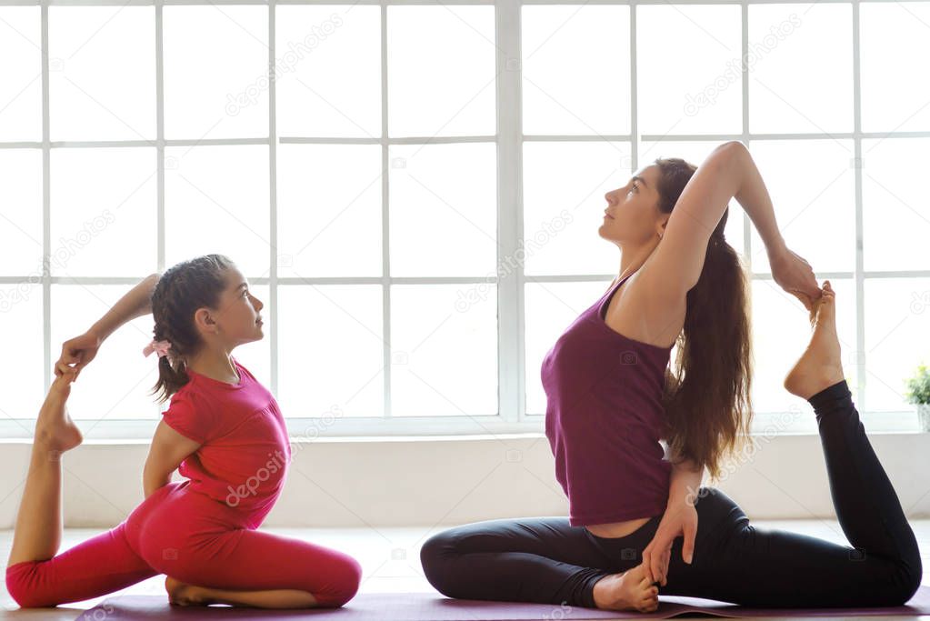 Young mother and daughter doing yoga exercise