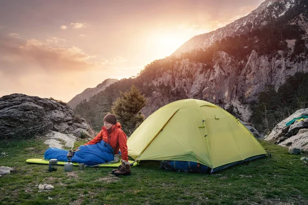 Vrouwelijke reiziger in slaapzak in de buurt van de tent in de bergen — Stockfoto