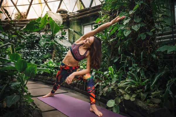 Giovane donna caucasica sorridente che fa esercizi di yoga all'orto botanico — Foto Stock