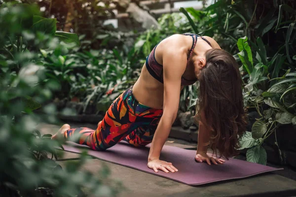 Junge kaukasische Frau praktiziert Yoga im botanischen Garten — Stockfoto