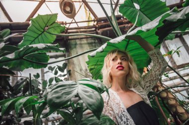 Genç kadın modeli ile egzotik flora çevrili beyaz