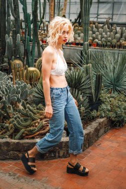 İnce neşeli kadın model güvenle succulents arasında yürüyüş