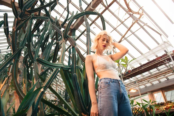 Fashion portrait of perky blonde model at greenhouse — Stock Photo, Image