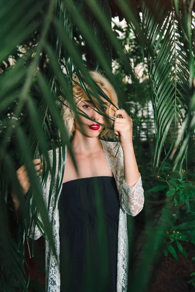 Regard mystérieux du modèle féminin regardant à travers les branches de palmier — Photo