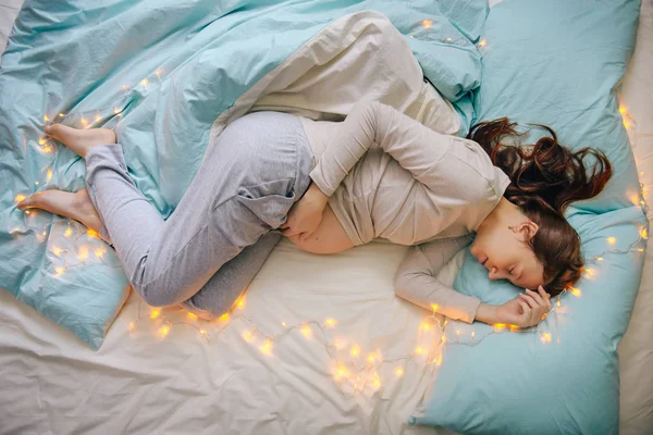 Беременная женщина спит на кровати — стоковое фото