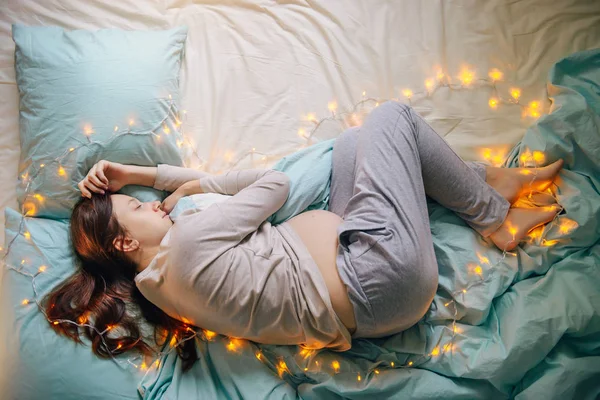 Беременная женщина спит на кровати — стоковое фото