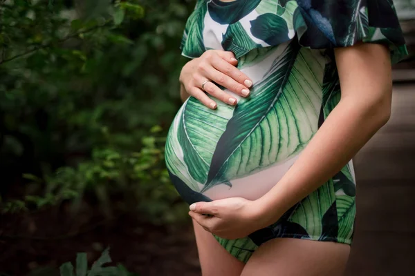 Vientre de mujer caucásica embarazada joven en traje de baño en la vegetación — Foto de Stock