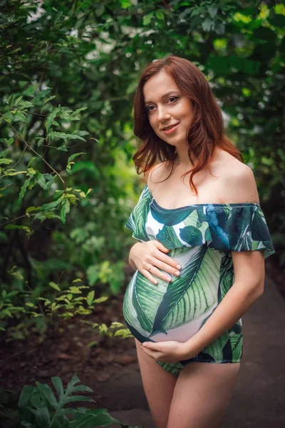 Beautiful young caucasian pregnant woman in swimsuit at tropical