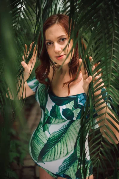Schöne schwangere kaukasische rothaarige Frau im Badeanzug in Palm l — Stockfoto