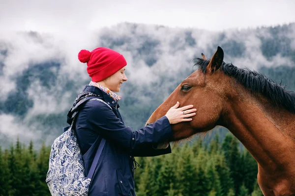 Mulher caminhante caucasiana se unindo com cavalo no vale da montanha — Fotografia de Stock