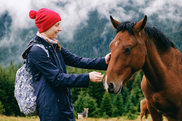 Caucasian female hiker bonding with horse in mountain valley