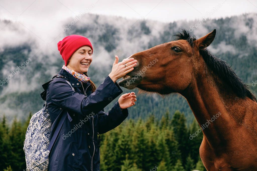 Caucasian female hiker bonding with horse in mountain valley