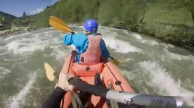 Bahar zamanı dağ nehrinde rafting yapan iki kişi. Olağanüstü profesyonel su sporu